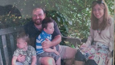 Duncan as a family carer outdoors with his partner and two young children, one sitting on his lap.