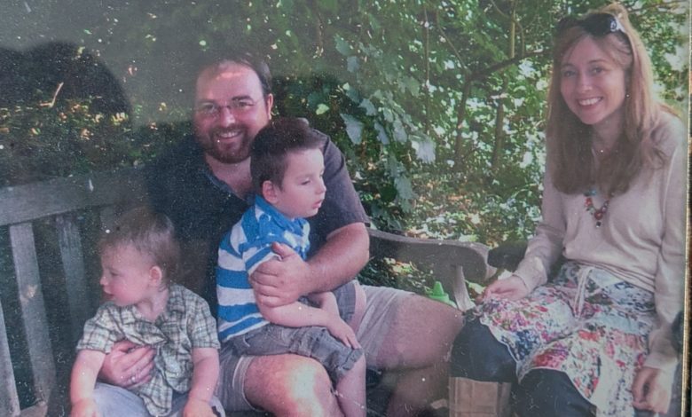 Duncan as a family carer outdoors with his partner and two young children, one sitting on his lap.