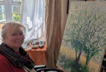 Clare, who has an incomplete spinal cord injury, painting at an easel with a Trabasack supporting her palette.