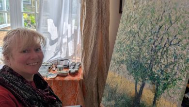 Clare, who has an incomplete spinal cord injury, painting at an easel with a Trabasack supporting her palette.