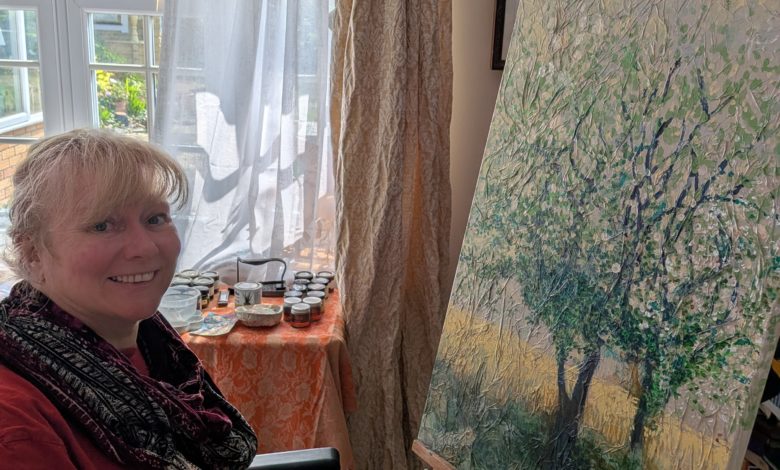 Clare, who has an incomplete spinal cord injury, painting at an easel with a Trabasack supporting her palette.