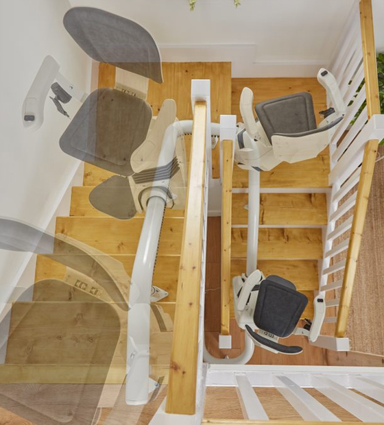 Curved stairlift shown at different positions along a wooden staircase with a central handrail.