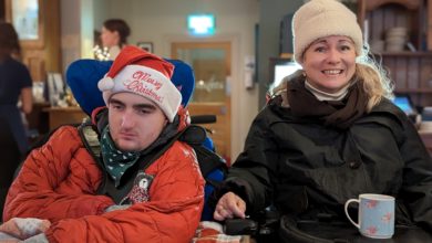 Two wheelchair users seated together, one using specialist supportive seating and the other with a Trabasack lap tray holding a mug.
